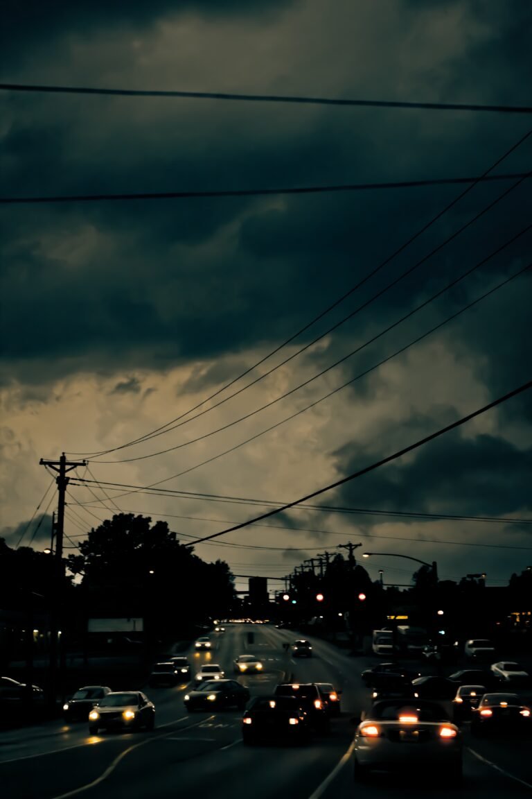 A vertical photo of a city street at night with many cars and dark clouds